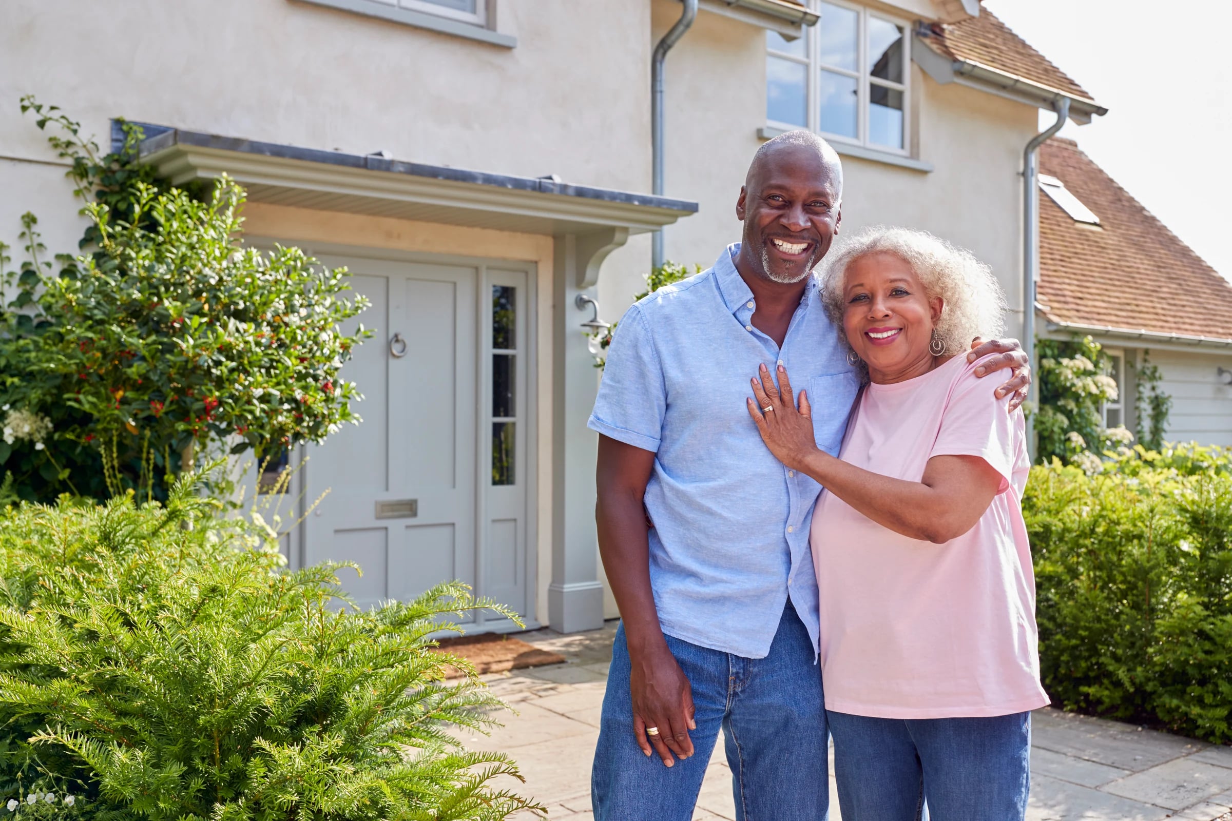 A smiling senior couple embracing in front of their home